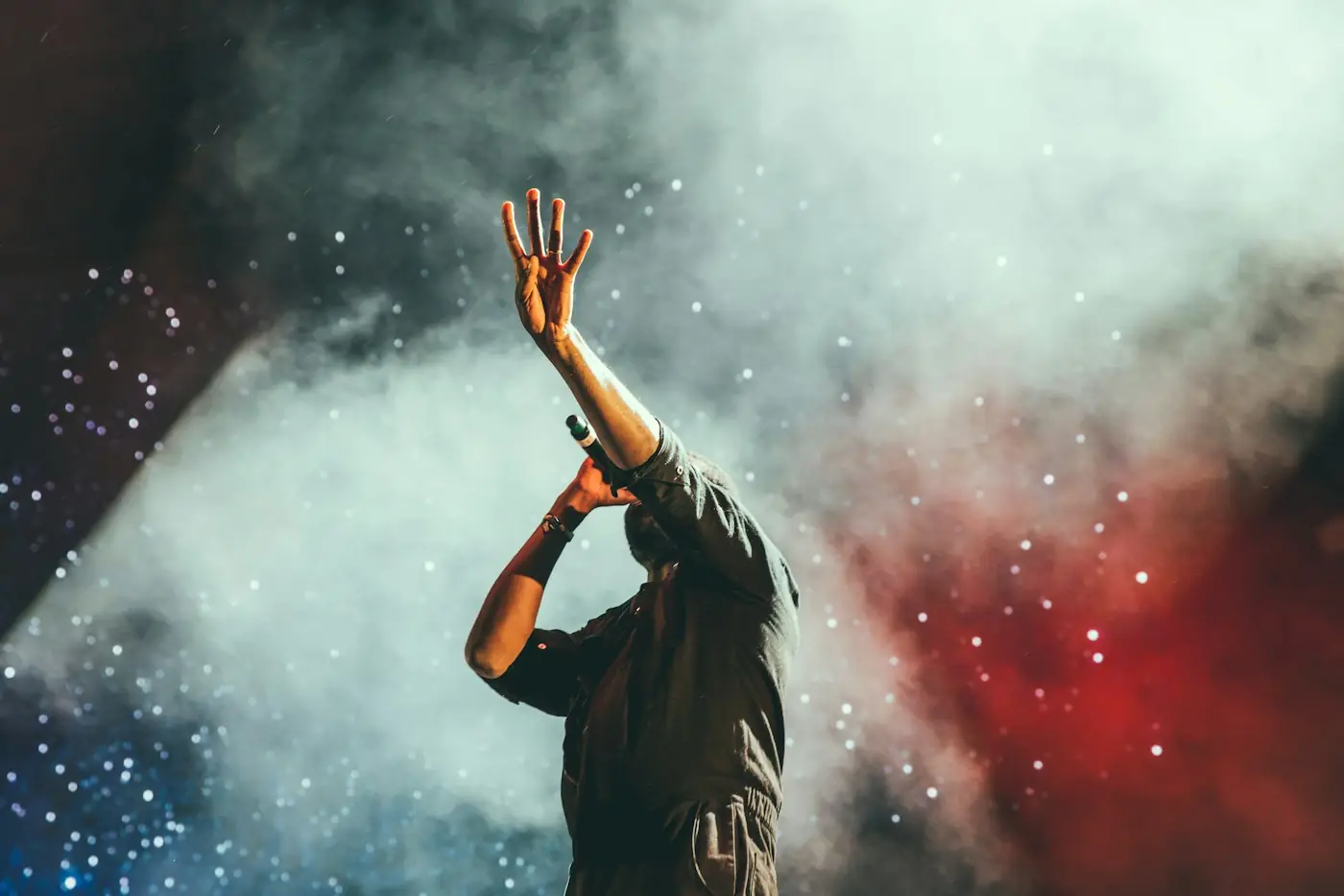 Joven levantando la mano en adoración entre humo y luces de colores